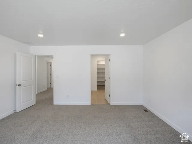 Interior space featuring neutral-toned carpeting, two-panel interior doors, recessed lighting, and a walk-in closet with built-in shelving