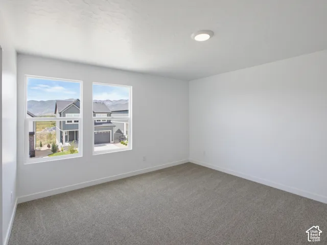 Neutral interior room featuring neutral carpeting, recessed ceiling lighting, and dual windows with mountain scenery