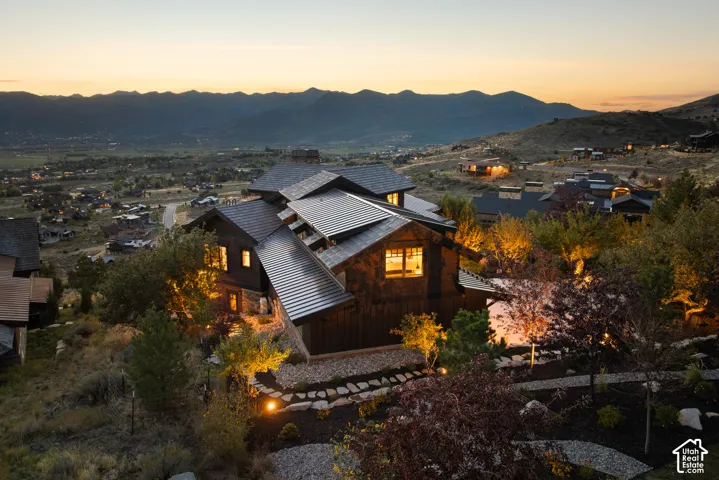 Multi-level mountain residence featuring dark vertical siding, stone masonry accents, a metal roof, and terraced landscaping