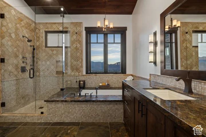 Bathroom featuring a walk-in shower with glass enclosure, soaking tub with tile surround, dark wood cabinetry, stone-finish countertops, and wood-paneled ceiling