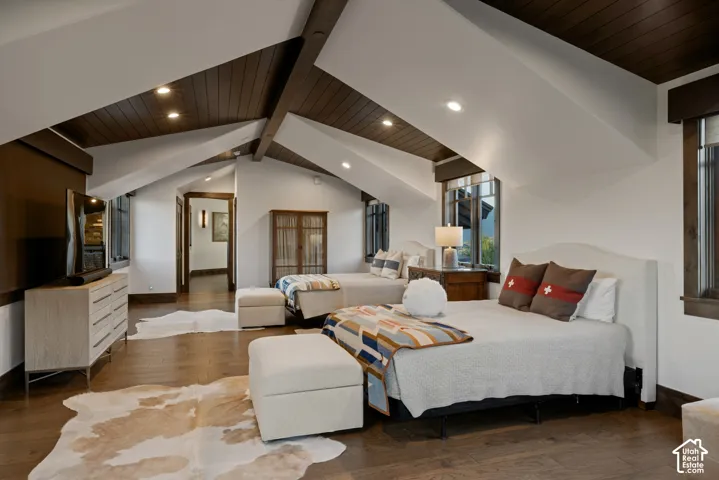 Vaulted ceilings with exposed wood-finish beams, recessed lighting, wood-finish flooring, and natural wood trim accents