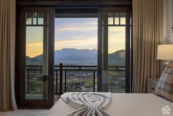 Multi-panel sliding glass doors with dark wood frames, metal balcony railing, and expansive mountain scenery