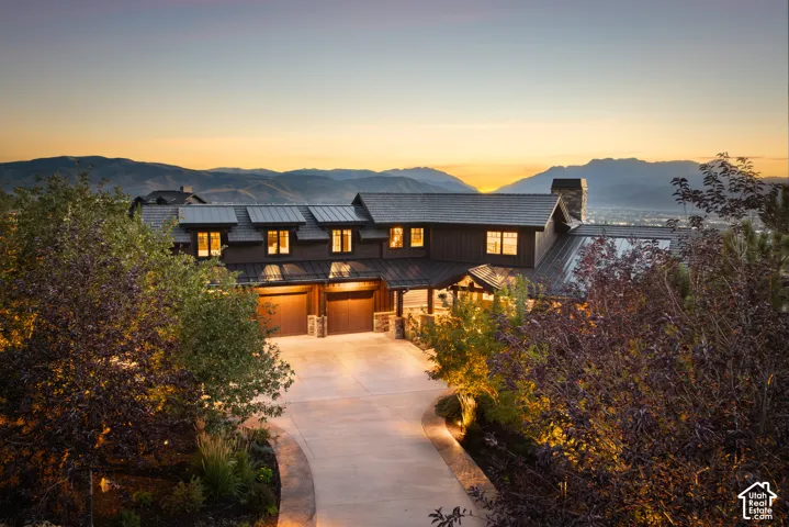 Custom residence featuring a mountain backdrop, metal roof, stone masonry accents, and a concrete driveway