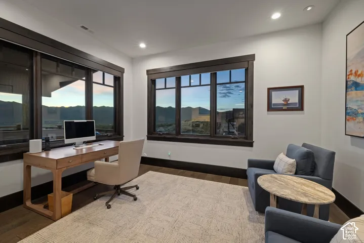 Room featuring large-pane windows with dark wood trim, mountain scenery, recessed lighting, and wood-finish flooring