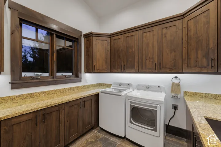 Custom stained wood cabinetry, stone countertops, under-cabinet lighting, and large-format tile flooring