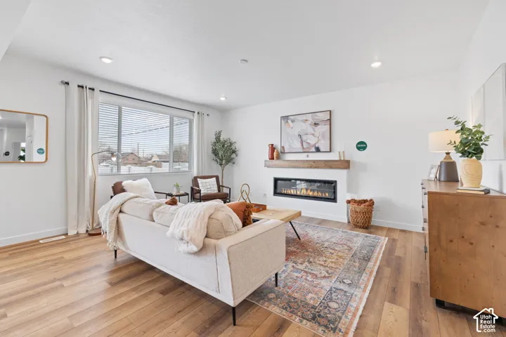 Living area featuring wood-finish flooring, a linear electric fireplace, a wood-beam mantel, and recessed lighting