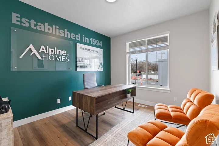 Interior space featuring wood-finish flooring, a neutral color palette, and a large window with white casing