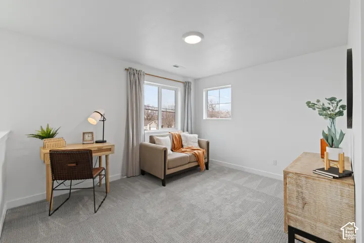 Neutral-toned interior featuring wall-to-wall carpeting, crisp white walls, flush-mount LED lighting, and two multi-pane windows