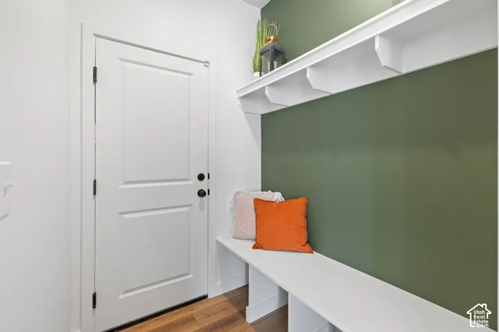 Built-in bench seating with integrated storage, wall-mounted display shelving, wood-finish flooring, and a solid-core paneled entry door