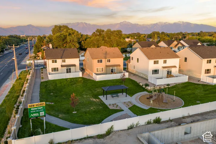 Communal outdoor space featuring a covered pavilion, concrete walkways, a playground, and mountain range scenery