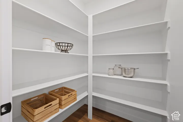 Pantry featuring white tiered shelving and wood-finish flooring