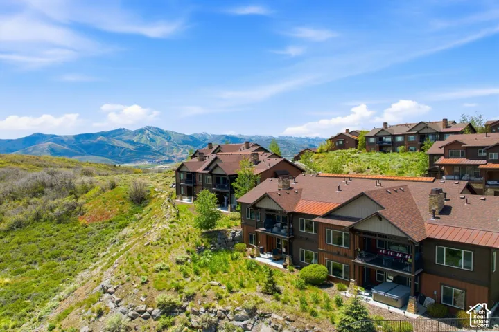 Multi-story exterior featuring wood-paneled siding, metal and shingle roofing, integrated balconies, and expansive mountain scenery