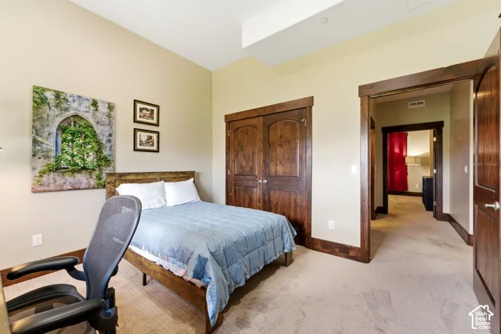 Bedroom featuring neutral wall paint, arched-top wood doors, matching wood trim, and carpeted flooring