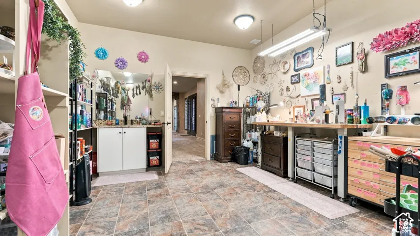 Tile flooring, built-in lower cabinetry with stone-finish countertops, wall-mounted mirror, and overhead fluorescent lighting