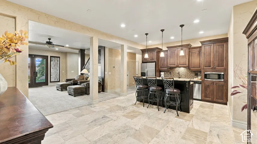 Kitchen featuring stained wood cabinetry, stone-tile flooring, granite countertops, and three pendant light fixtures