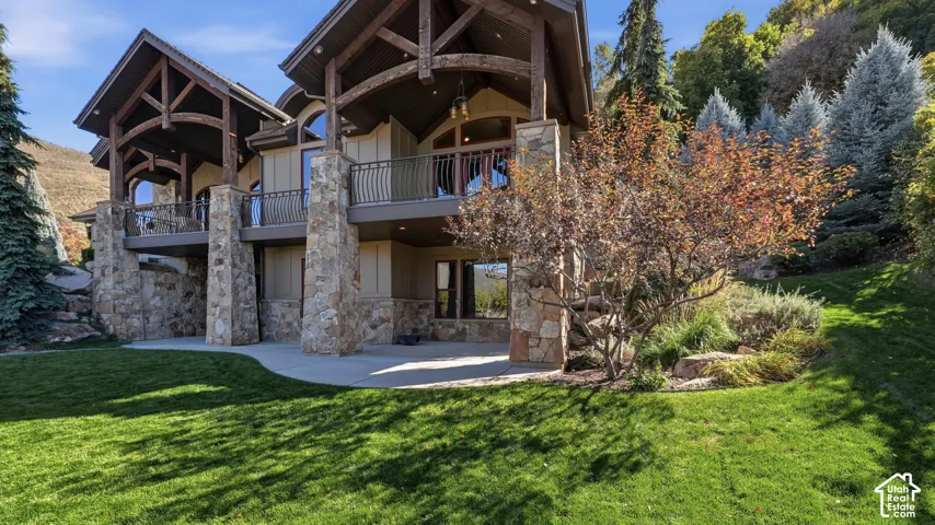 Timber-framed exterior with stone-clad pillars, multi-level balconies, wrought-iron railings, and a concrete patio