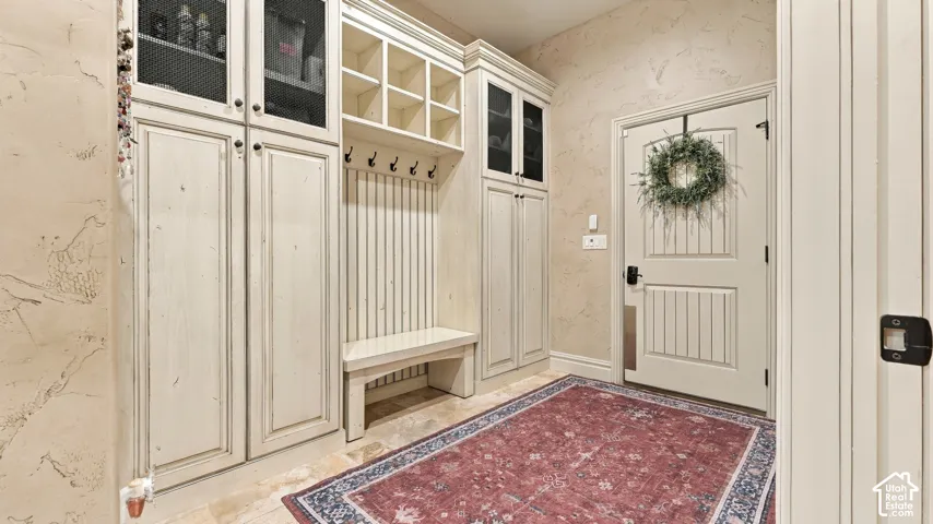 Custom built-in cabinetry featuring glass-fronted upper doors, open shelving, a bench seat, and integrated wall hooks