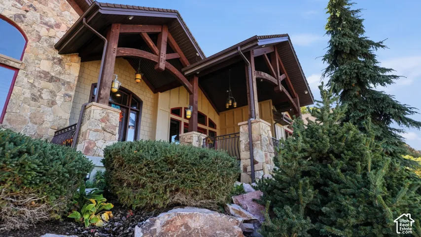 Exterior facade featuring stone masonry, timber-frame gable accents, covered porch, and integrated architectural lighting