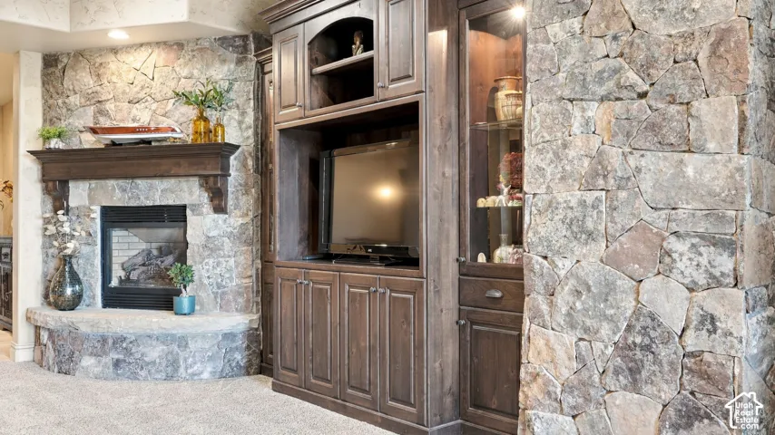 Floor-to-ceiling natural stone masonry, custom dark-stained wood built-in cabinetry with glass-front display shelving, and a prominent stone fireplace hearth with a matching wood mantel