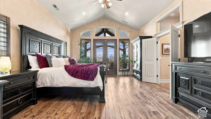 Vaulted ceiling featuring a central fan, wood-finish flooring, and expansive windows with transom glass