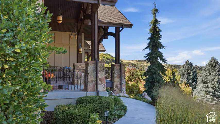 Covered porch featuring wood-post timber framing, stone pillar bases, decorative iron railings, and pendant lighting