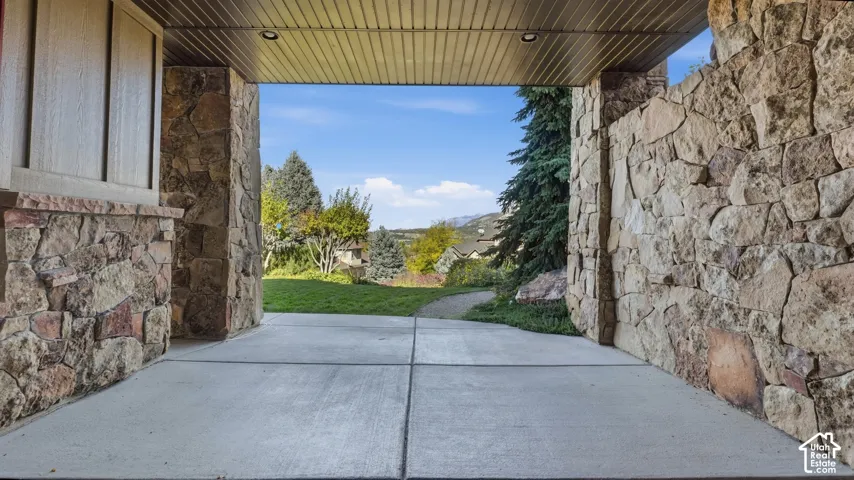 Covered patio featuring stone masonry columns, recessed ceiling lighting, concrete flooring, and an expansive mountain backdrop
