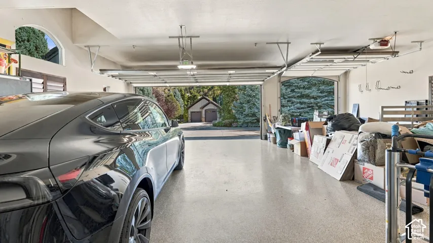Three-car garage featuring epoxy flooring, arched window detailing, and integrated overhead lighting