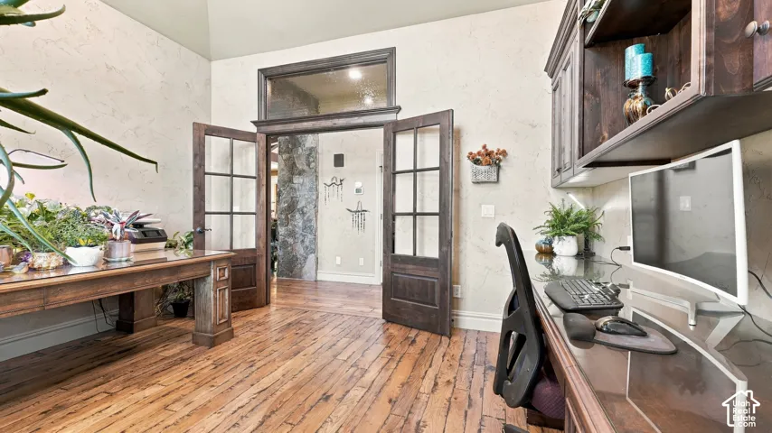 Wood-finish flooring, double French doors with glass panes, transom window, and built-in dark wood cabinetry