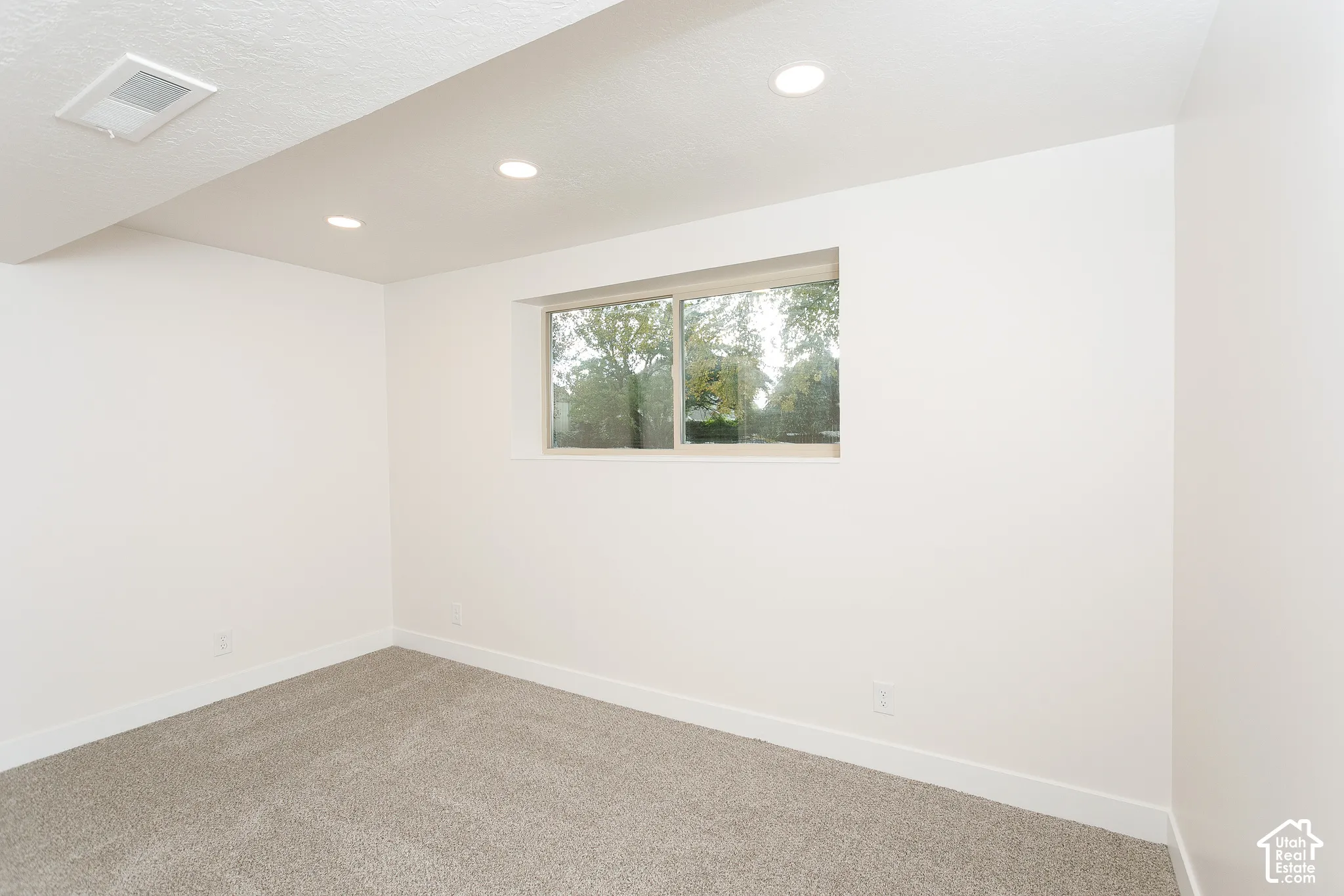 Neutral-toned carpeting, recessed ceiling lighting, and a horizontal sliding window