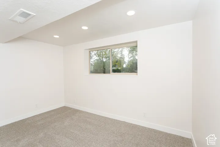 Neutral-toned carpeting, recessed ceiling lighting, and a horizontal sliding window