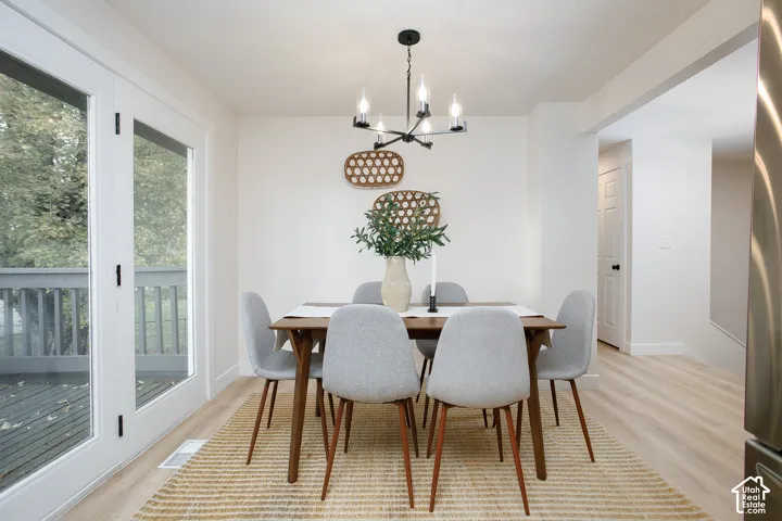 Dining space featuring light-toned wood-finish flooring, a multi-arm chandelier, and double glass doors providing external access