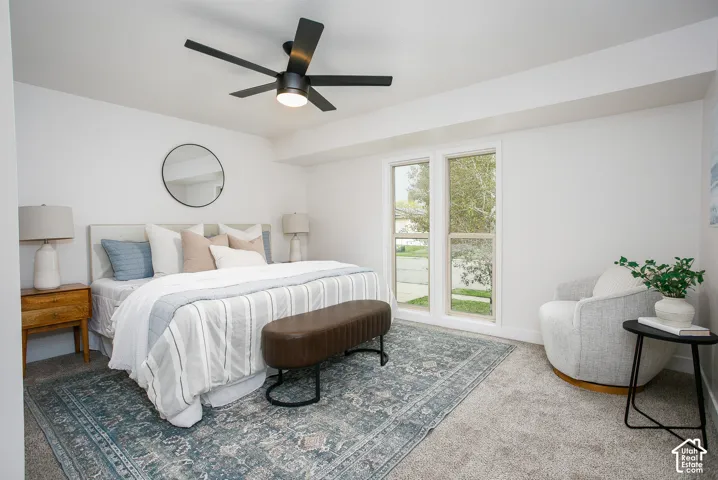 Neutral-toned interior space featuring recessed tray ceiling, matte black five-blade ceiling fan with integrated lighting, wall-to-wall carpeting, and dual-pane vertical windows