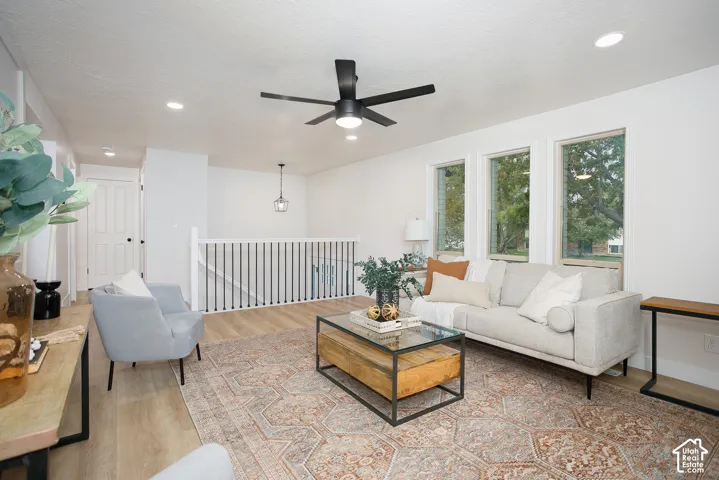 Interior featuring wood-finish flooring, recessed lighting, matte black ceiling fan, and white railing with black balusters