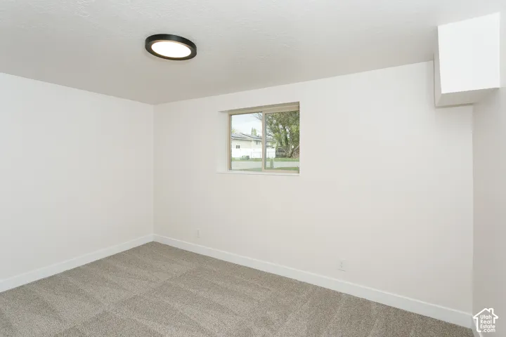 Neutral-toned carpeting, minimalist ceiling-mounted LED fixture, sliding window, and finished white wall surfaces