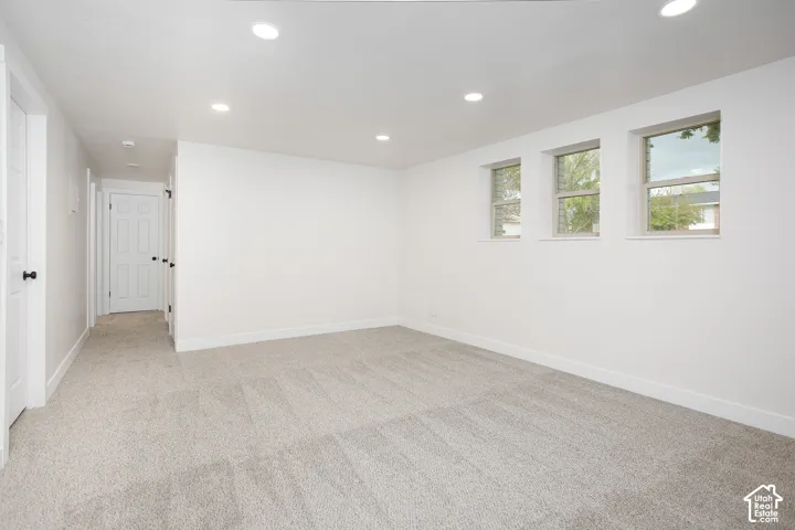 Neutral interior featuring wall-to-wall carpeting, recessed ceiling lighting, and three double-pane windows