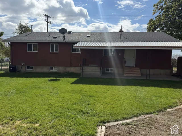 Brick exterior featuring a covered patio, concrete steps, and a spacious lawn