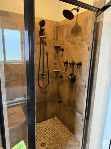 Walk-in shower featuring tile surrounds, an integrated tiled bench, a multi-head shower system, oil-rubbed bronze fixtures, and a glass enclosure