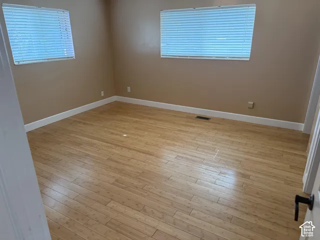 Wood-finish flooring, two windows featuring horizontal blinds, and smooth-finish wall surfaces