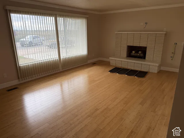 Wood-finish flooring, floor-to-ceiling vertical blinds, and a masonry fireplace featuring a tiered hearth