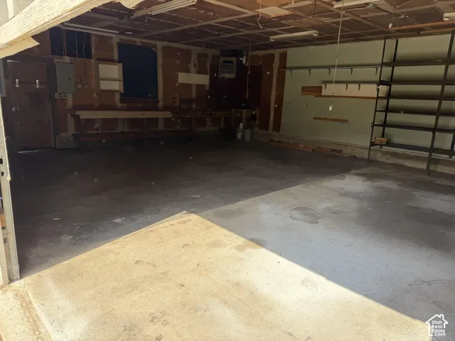 Multi-car garage featuring a concrete floor, built-in wooden workbench, and integrated metal shelving units
