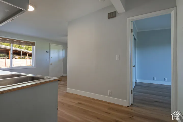 Interior featuring light-toned wood-finish flooring, a double-basin stainless steel sink, a recessed ceiling light, and white interior door frames