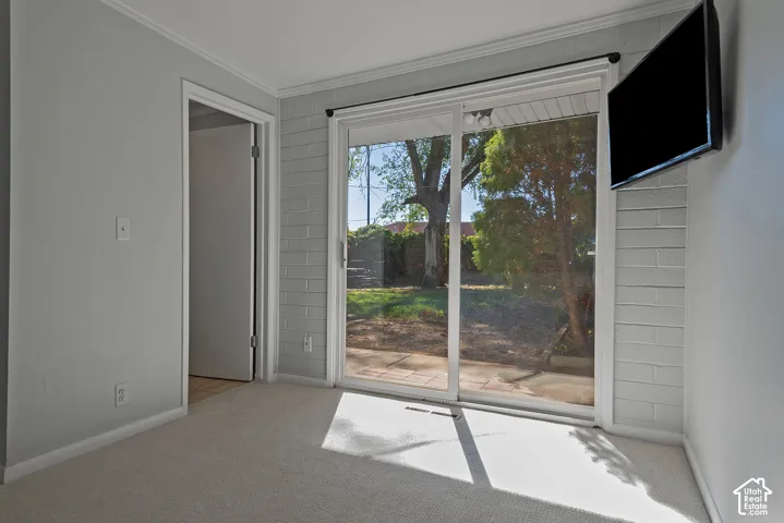 Sliding glass door featuring a painted brick accent wall, neutral carpeting, and exterior brick patio access