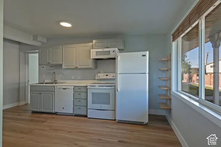 Kitchen featuring grey cabinetry, white countertops, built-in appliances, wood-finish flooring, and floating wall shelving