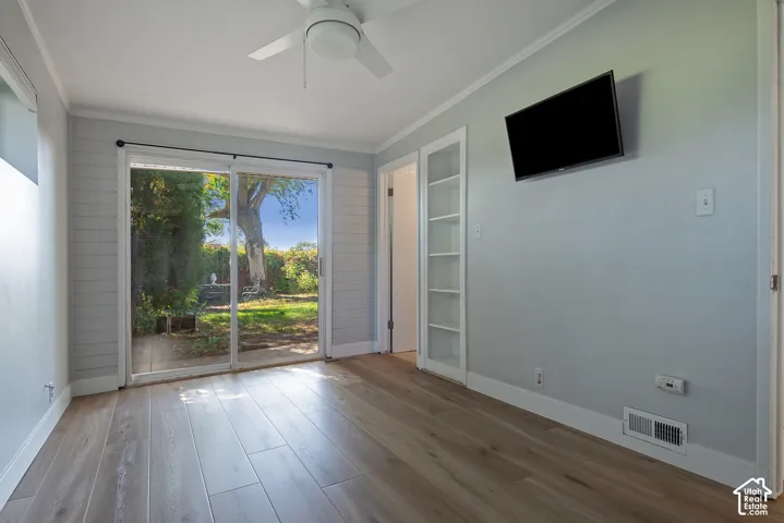 Wood-finish flooring, horizontal shiplap wall accents, sliding glass door, and built-in shelving unit