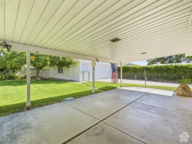 Covered patio with concrete slab, expansive lawn, and detached garage
