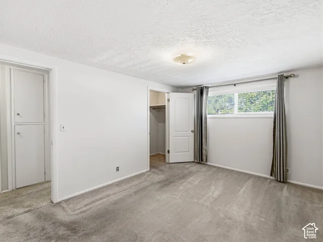 Recessed closet with white bi-fold doors, white interior door, light-colored carpet flooring, and a flush-mount ceiling light fixture