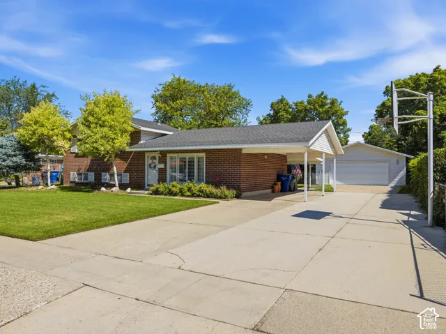 Brick exterior with white trim, carport, attached garage, and concrete driveway