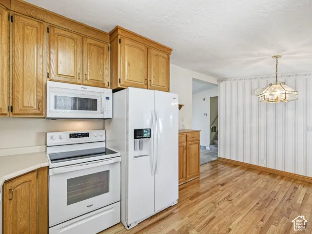 Kitchen featuring wood-finish cabinetry, white appliances, and a built-in microwave
