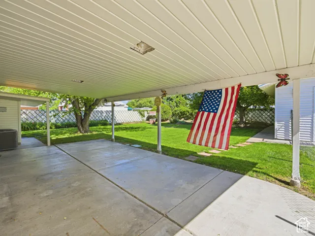 Covered concrete patio with a slatted ceiling, supported by white posts