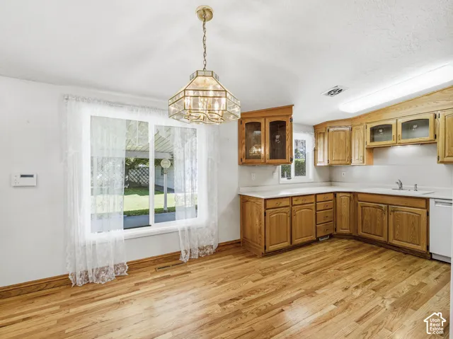 Wood-finish flooring, recessed lighting, and a kitchen with wood cabinetry, a stainless steel sink, and white countertops